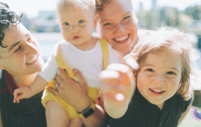 Happy LGBTQ family frolicking in a sunny city street