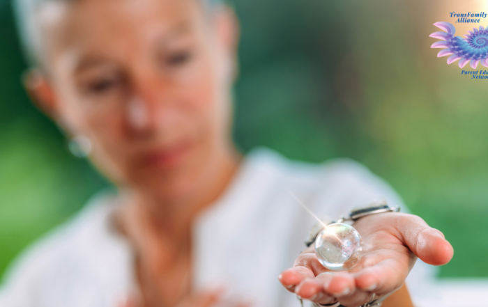 Figure of a person with a verdant green background observing a glass sphere in their outstretched hand, contemplating how to support your child's gender transition as a parent