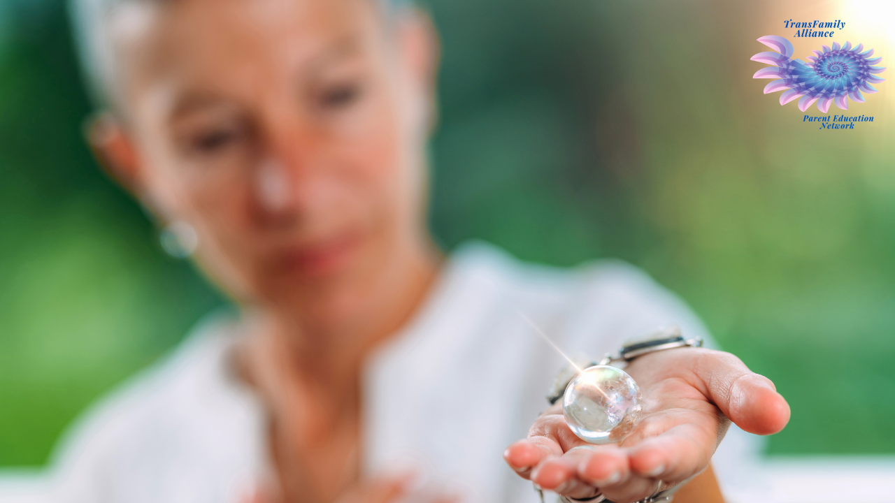 Figure of a person with a verdant green background observing a glass sphere in their outstretched hand, contemplating how to support your child's gender transition as a parent