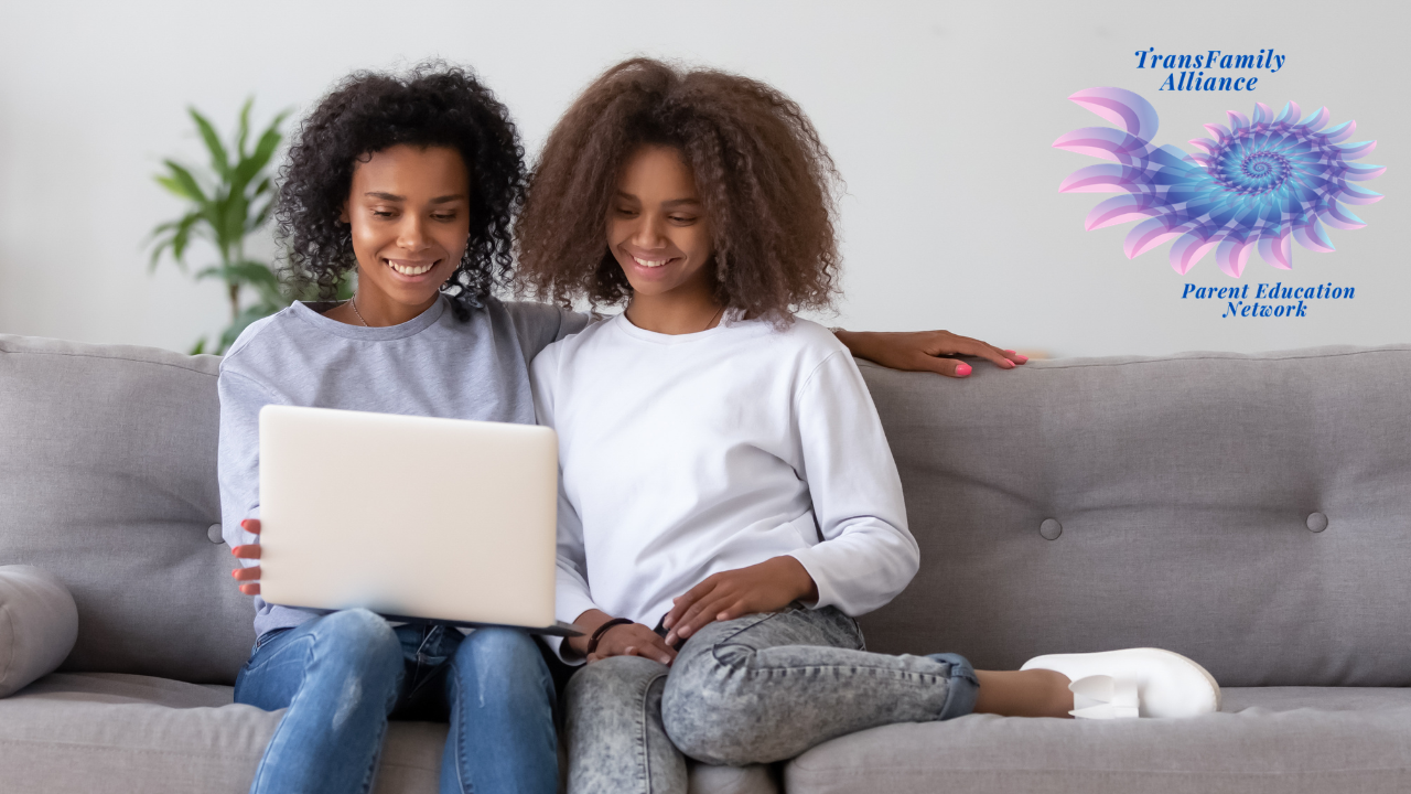 Parent and child cozy on a living room couch sharing a laptop as they consult the Internet for resources for parents of trans youth